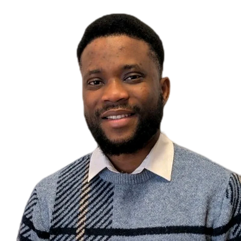 Taiwo Adekola smiling, wearing a grey patterned sweater over a white collar